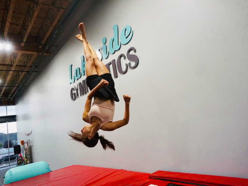 A woman is doing a handstand in front of a wall that says la vida gymnastics