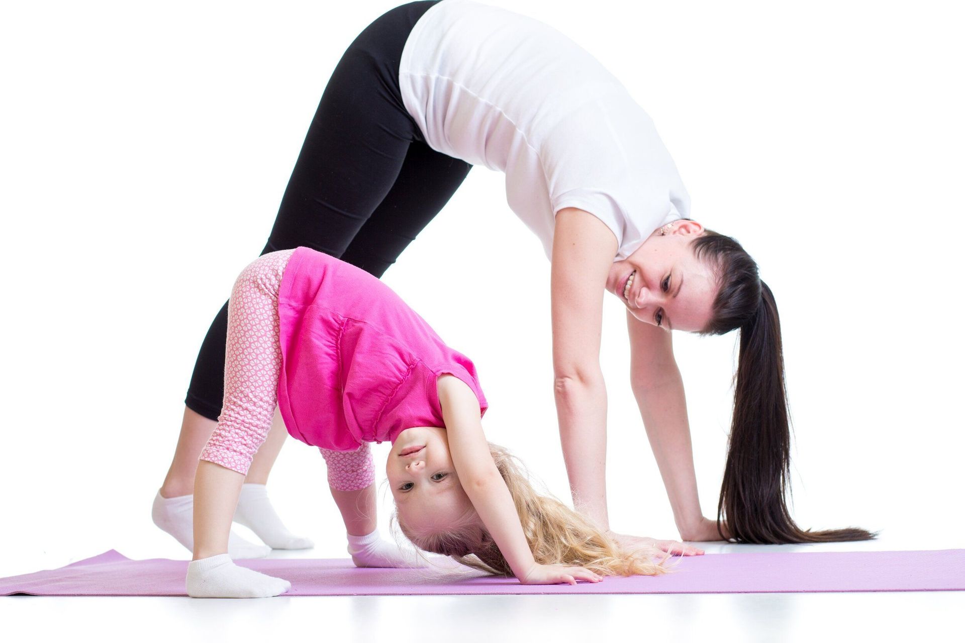 A woman and a little girl are doing yoga on a yoga mat.