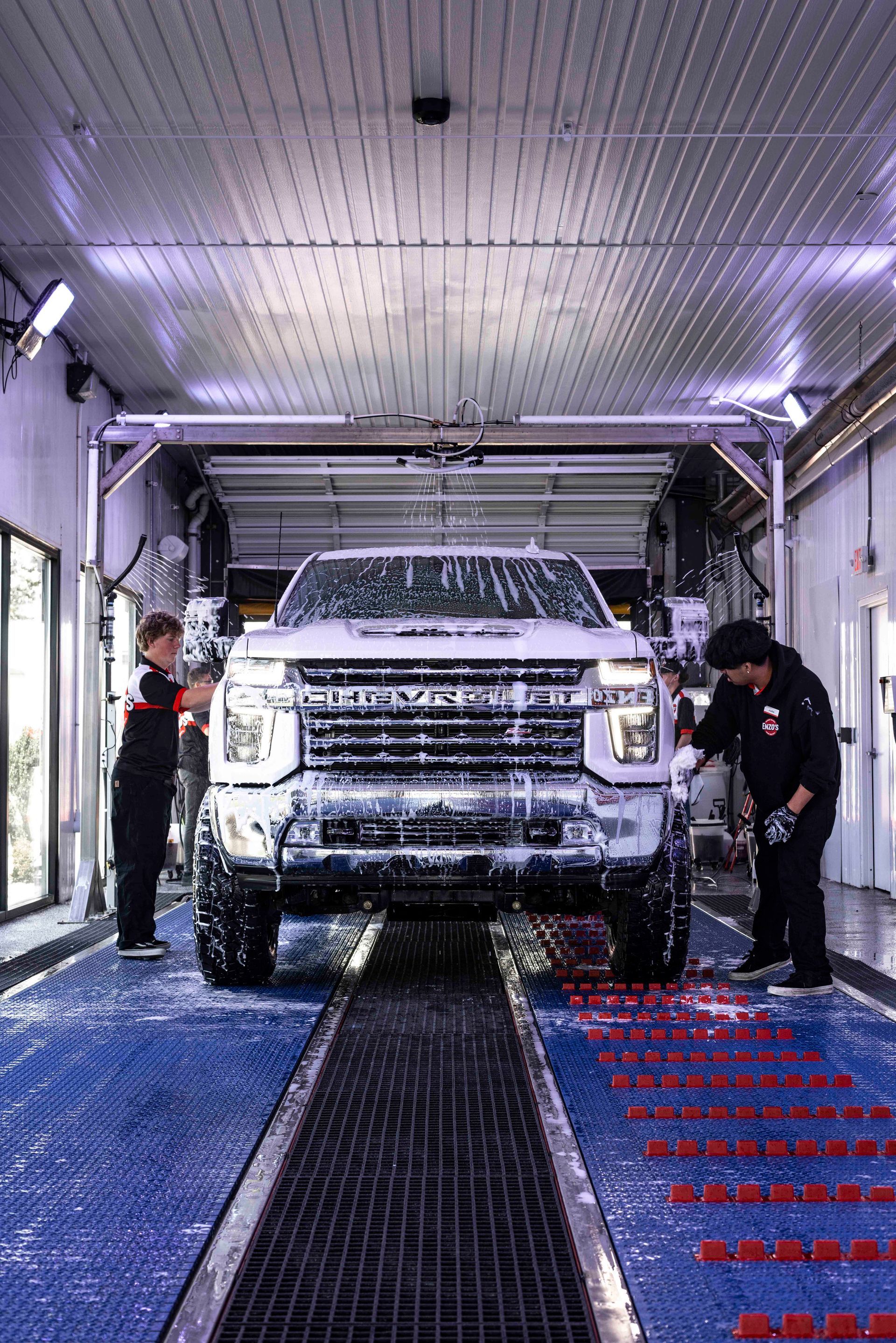 A person is cleaning a blue car with an orange towel
