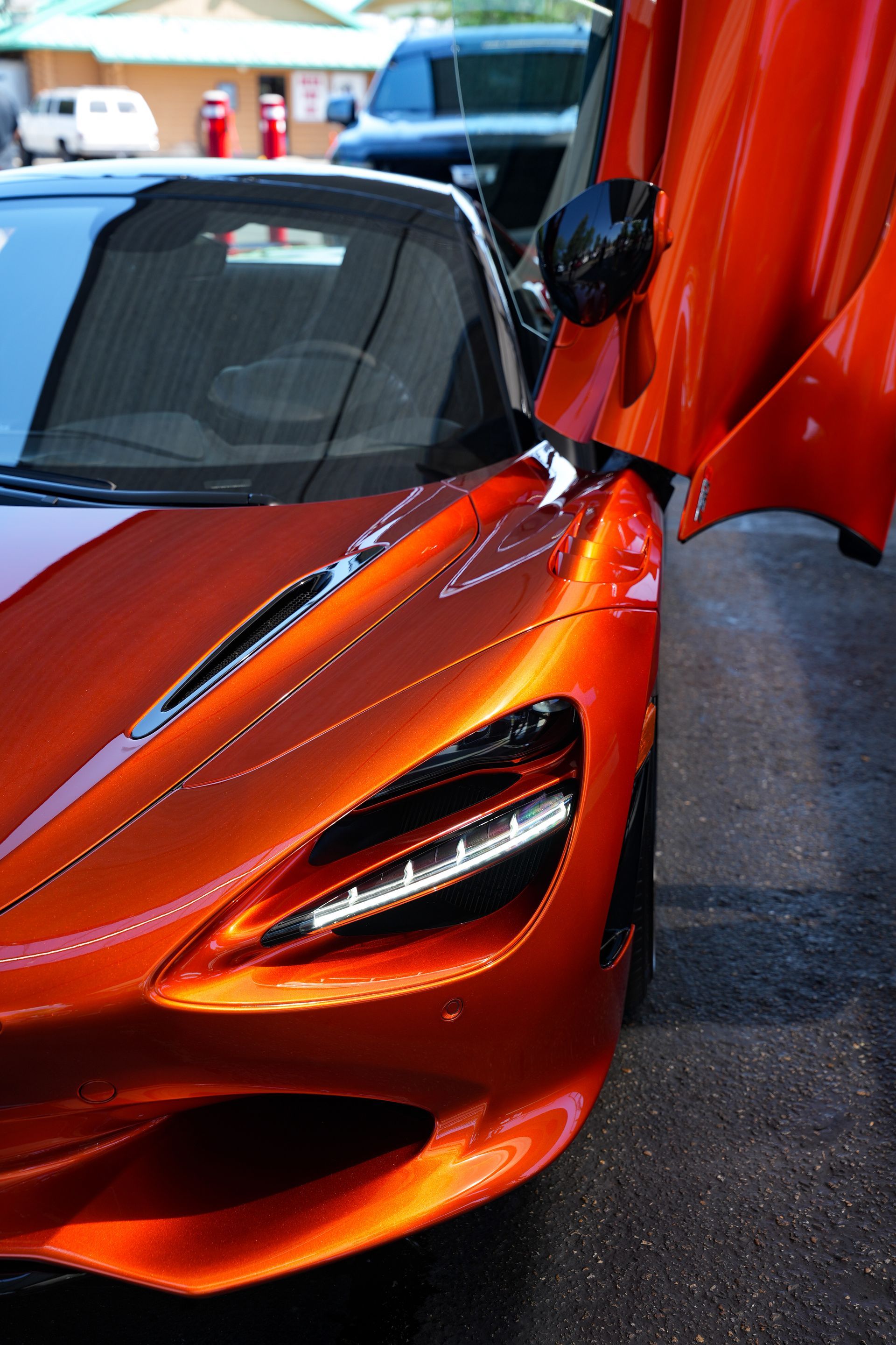 Orange McLaren sports car with doors open.