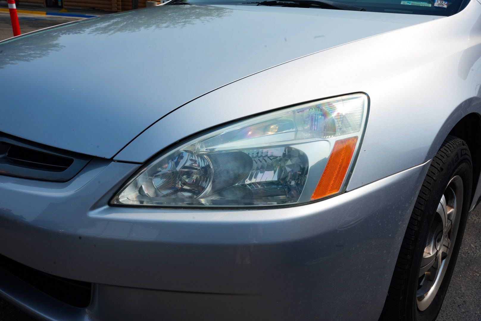 Silver car, front view, headlight with faded plastic and amber turn signal.