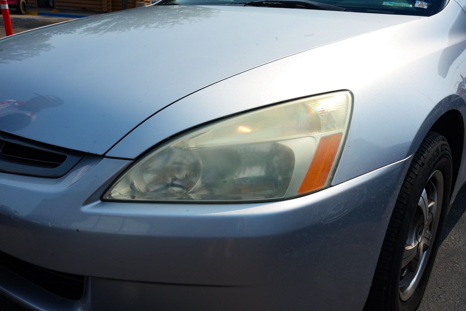 Silver car with a hazy headlight.