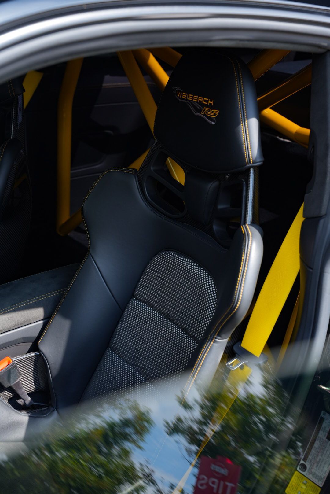 A person is cleaning a blue car with an orange towel