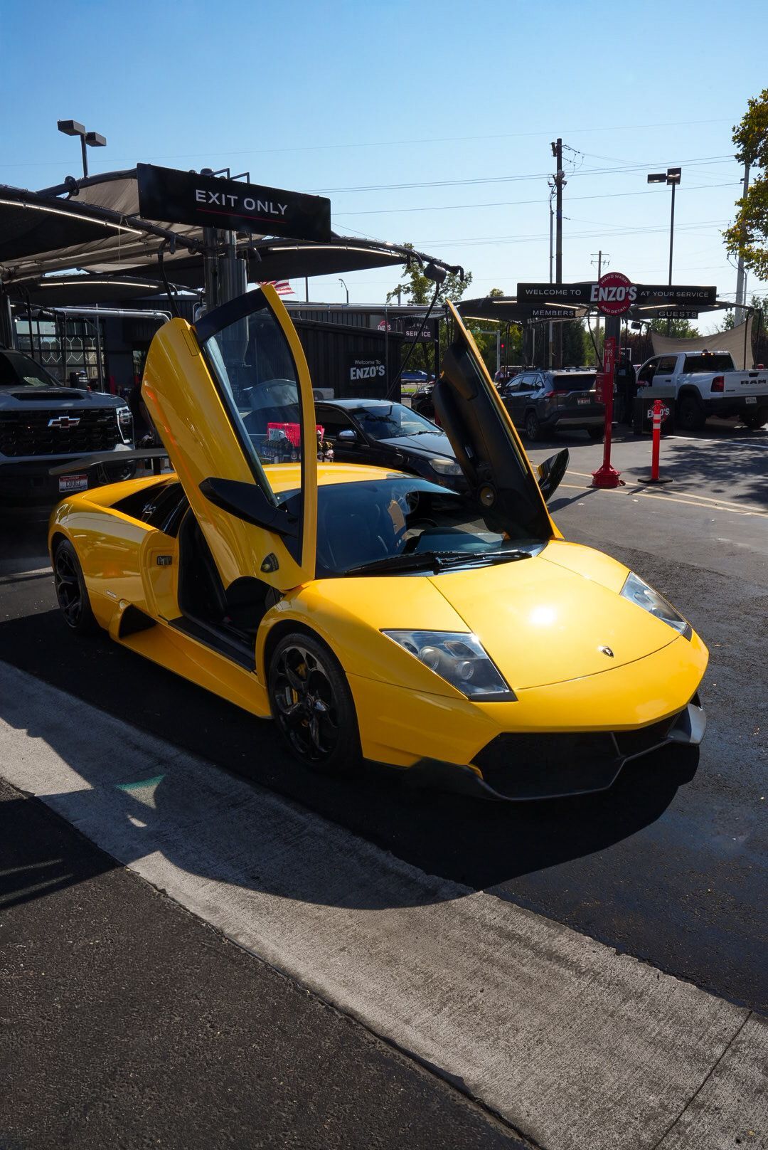 Yellow Lamborghini with doors open at a car wash.