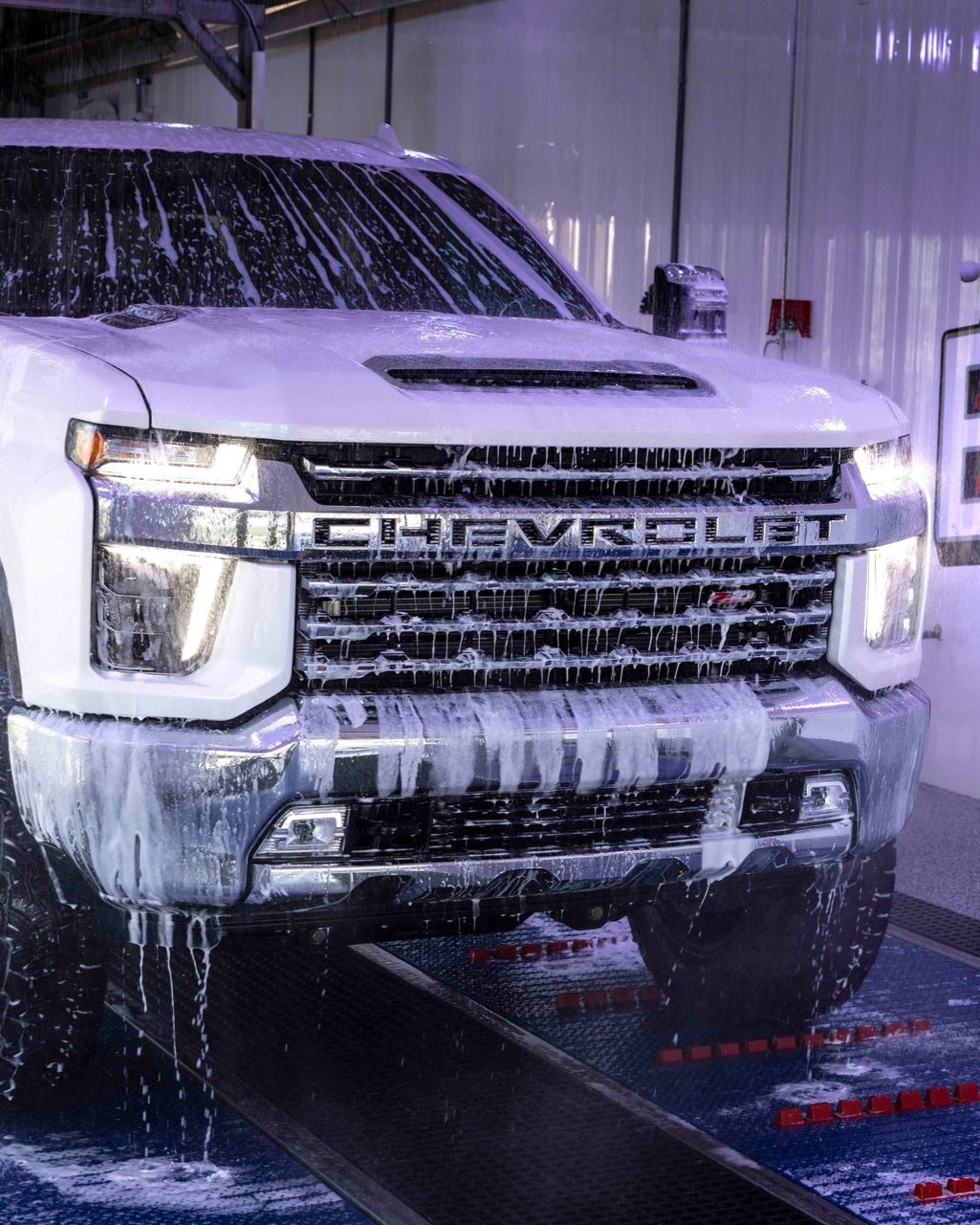 White Chevrolet pickup truck covered in soap at a car wash.