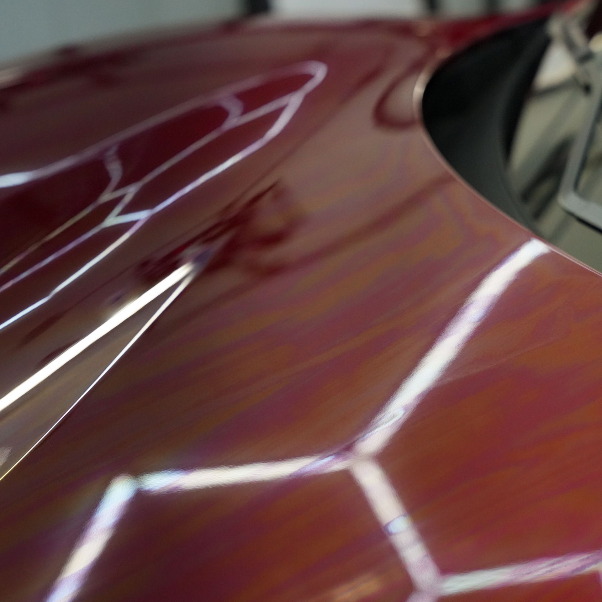 Red car hood reflecting light in a geometric pattern.