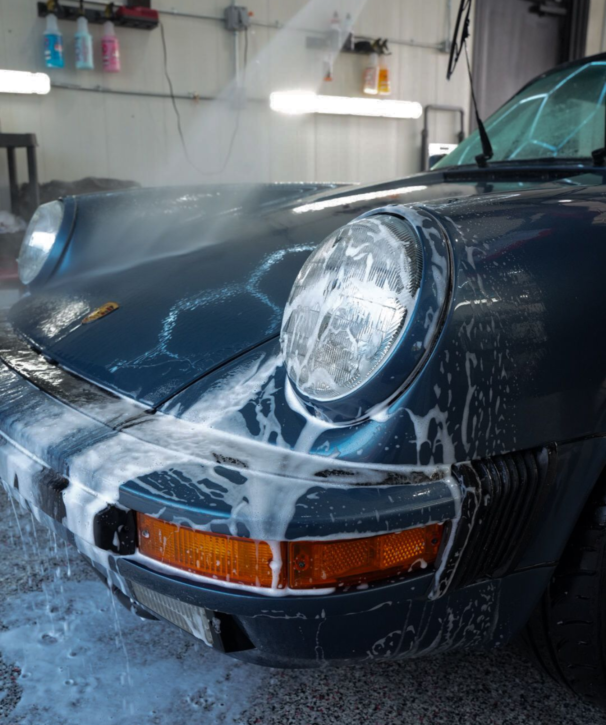 A man is cleaning the wheel of a black car with a sponge.