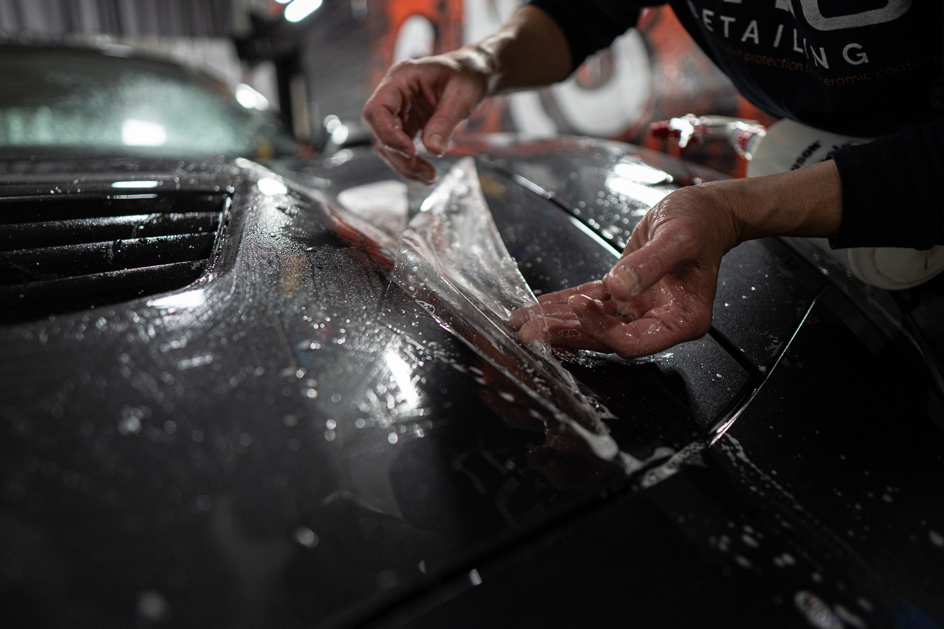 A man is working on a blue car in a garage.