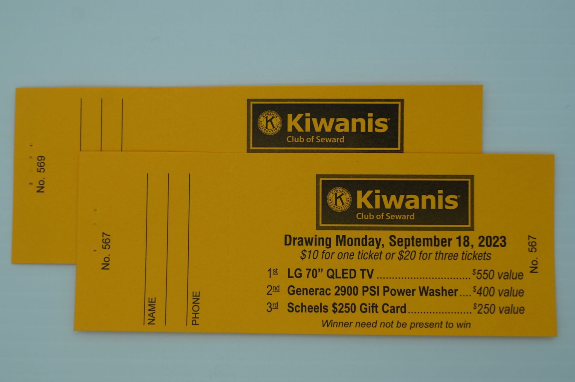 Two yellow kiwanis tickets are stacked on top of each other