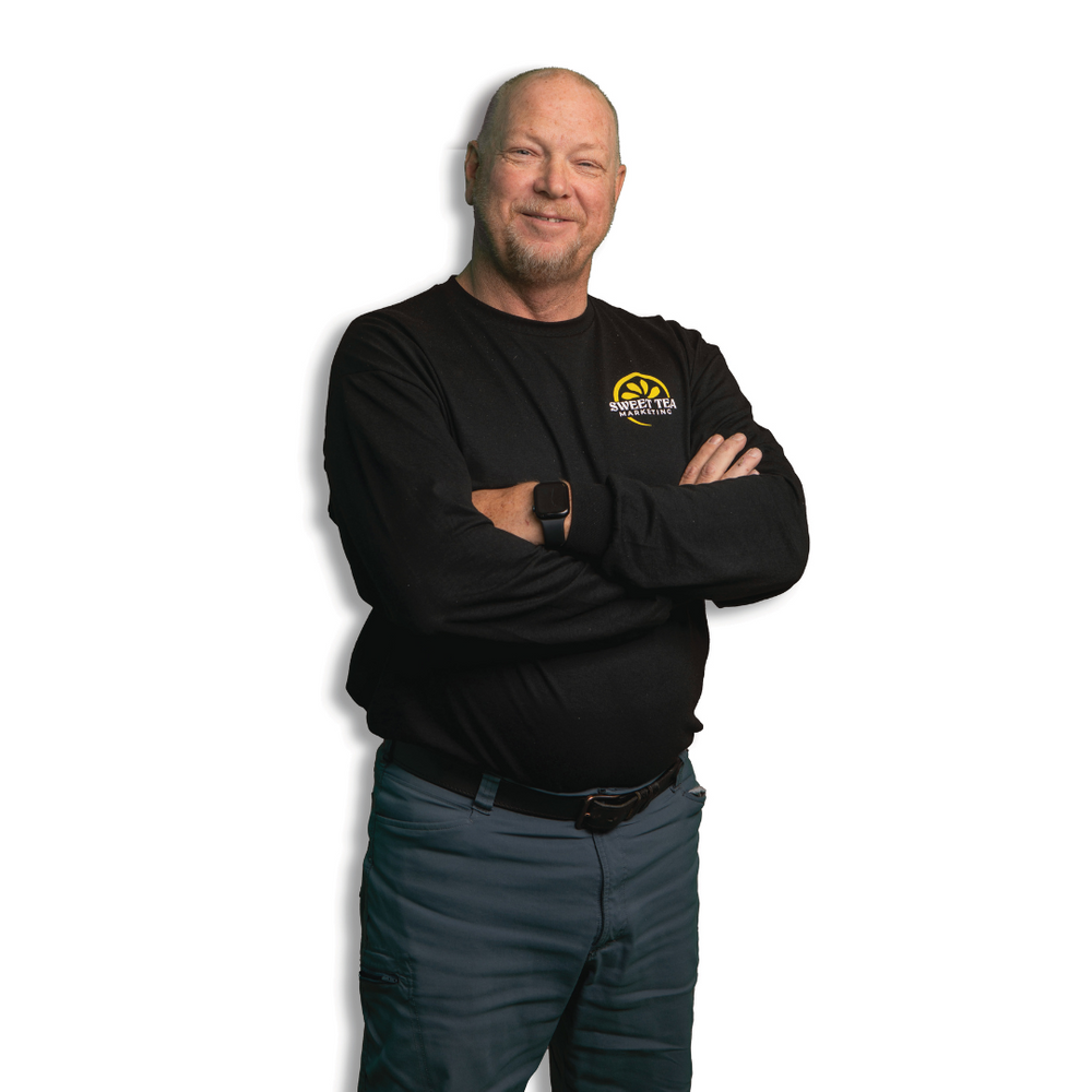 A man is standing with his arms crossed and wearing a black shirt that says gs