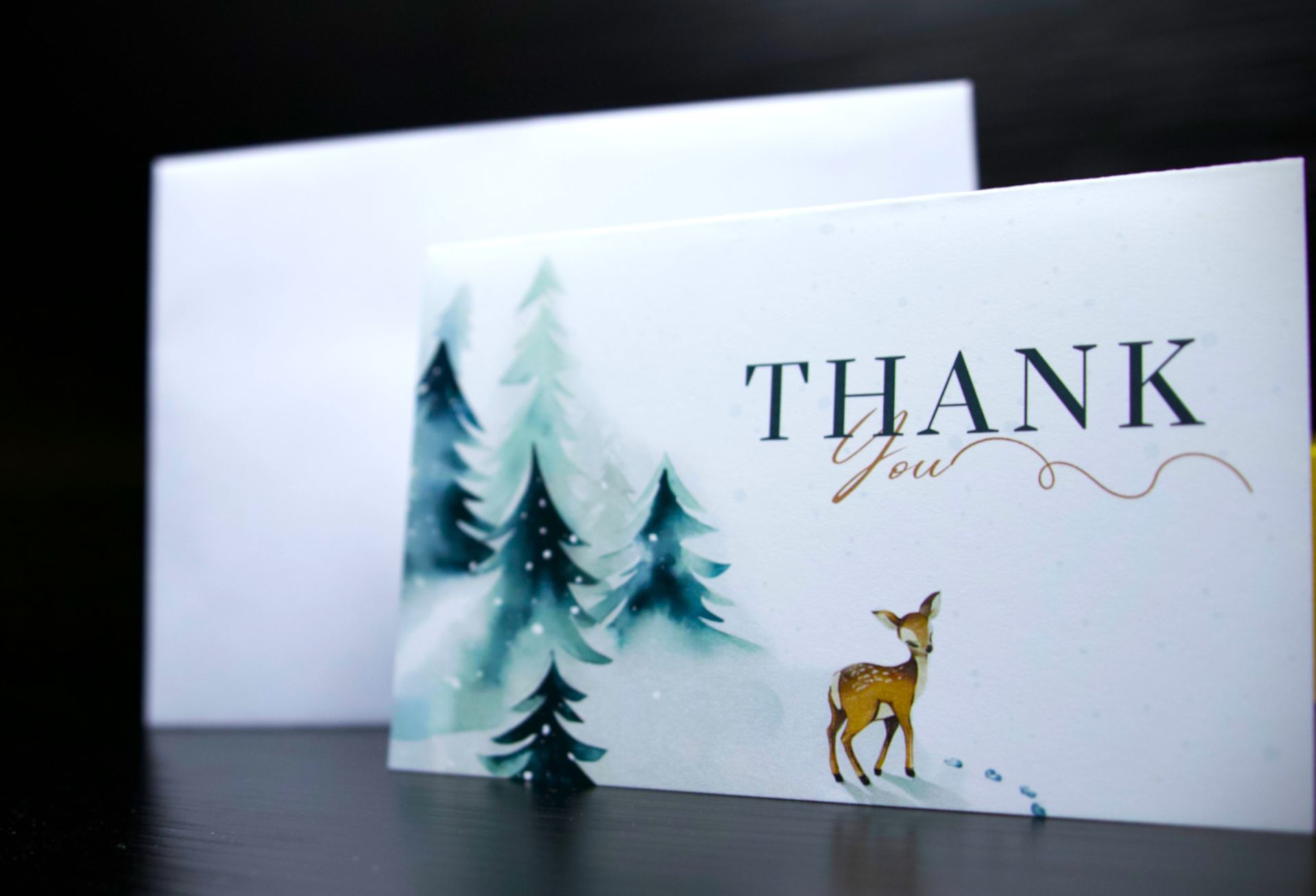 A thank you card with a deer and trees on it