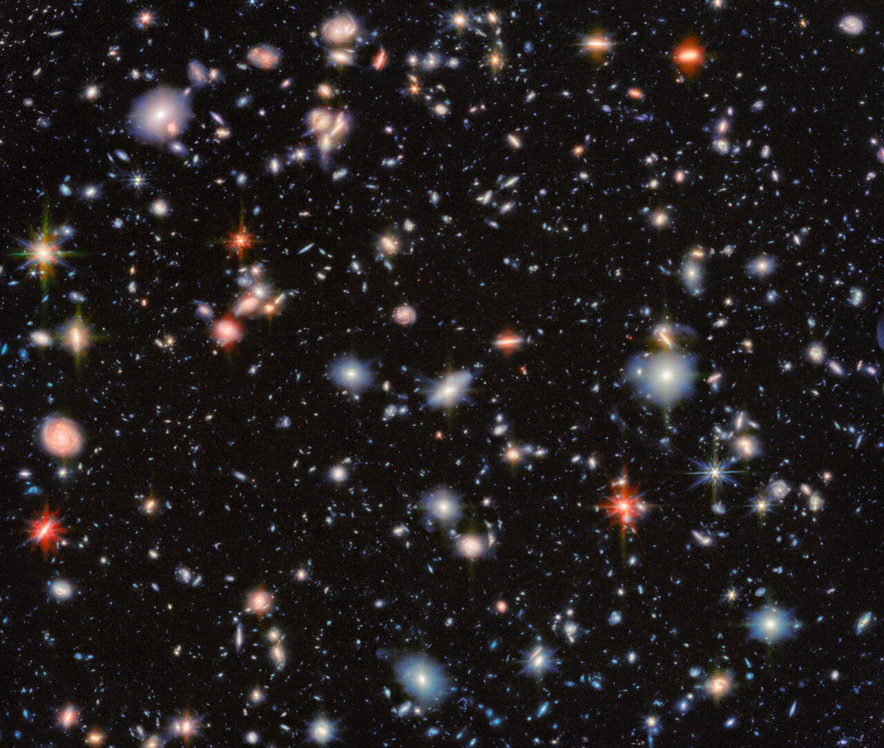Deep field view of countless galaxies, appearing as colorful dots against a dark background.
