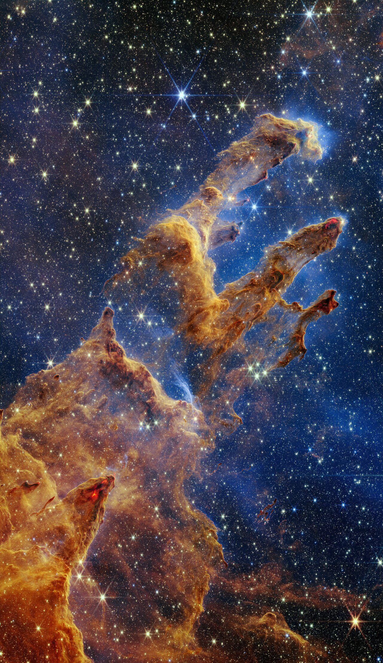 Nebula pillars in space, with brown and orange dust clouds against a starry blue background.