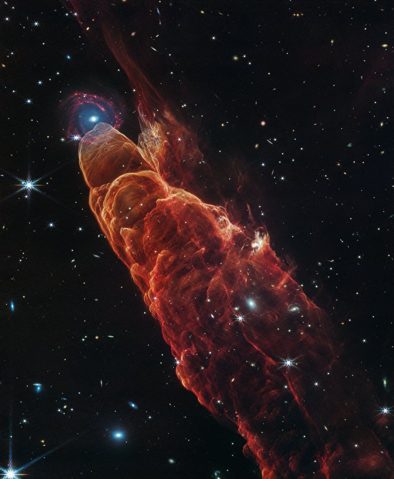 Red and orange cosmic pillar in space, with a bright star at its tip. Surrounding stars.