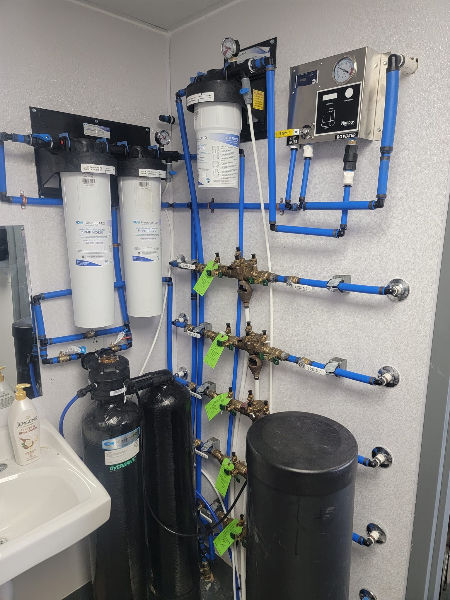 A bathroom with a sink and a lot of pipes hanging on the wall.