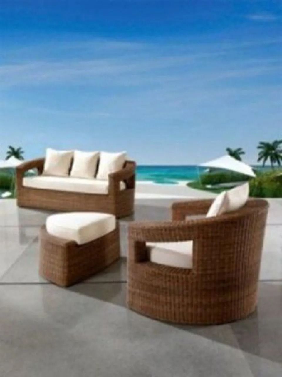 Set di mobili da esterno in vimini con cuscini bianchi su un patio con vista sull'oceano.