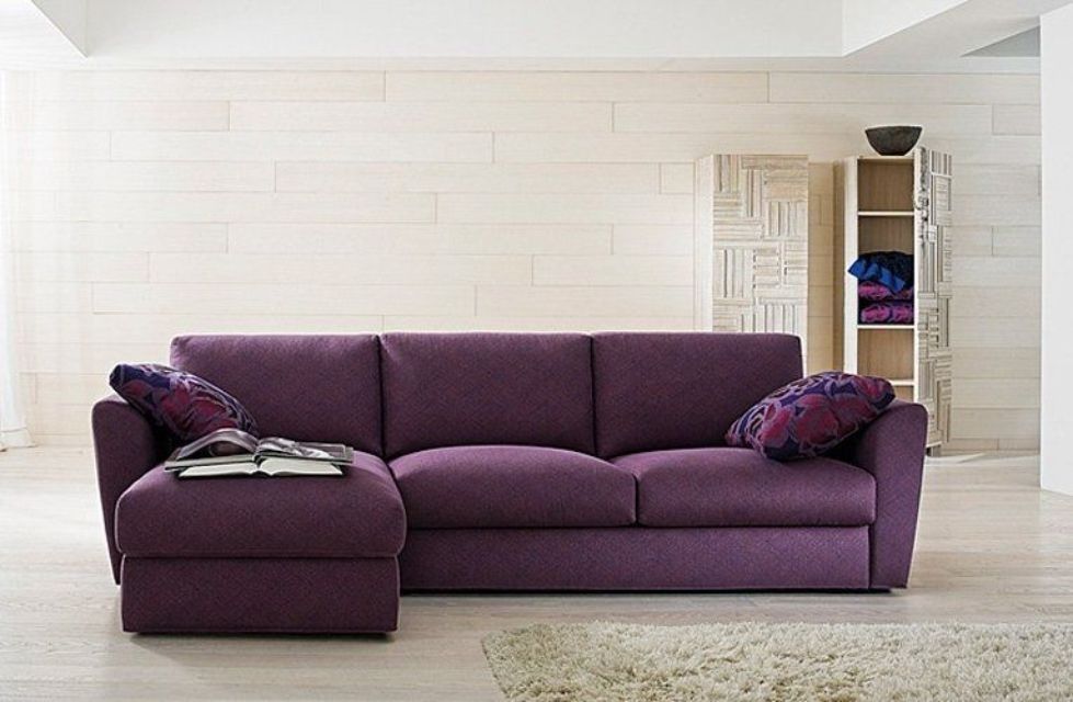 Divano componibile viola con due cuscini decorativi in ​​un soggiorno moderno.
