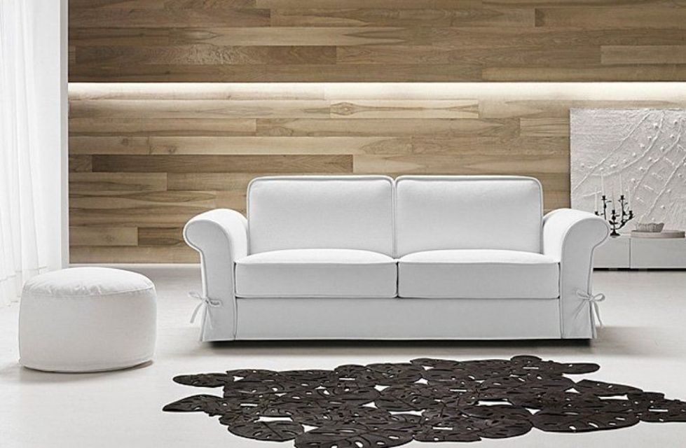 Divano bianco e pouf in una stanza moderna con pannelli in legno e un tappeto a fantasia scura.