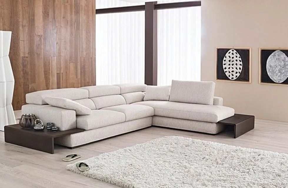 Divano componibile beige in un soggiorno moderno con un soffice tappeto bianco e opere d'arte.