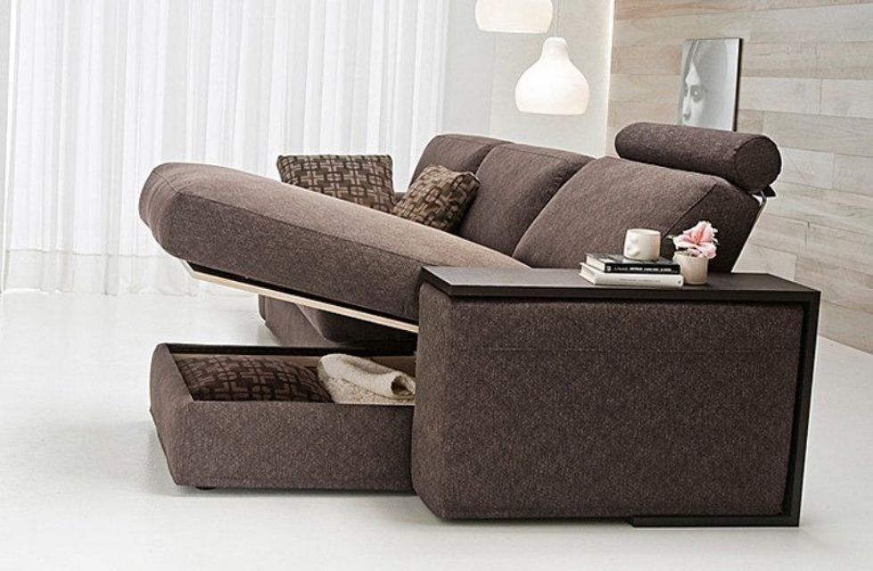 Divano marrone con contenitore e cassetto estraibile. Tavolino con libri e fiori.