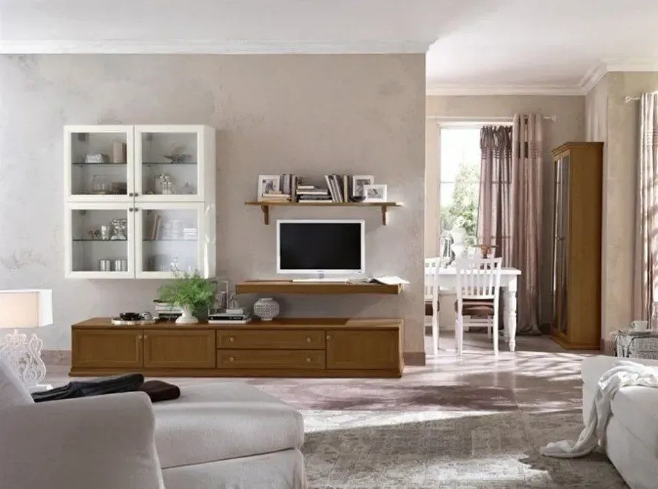 Soggiorno con mobile TV marrone, mobili bianchi e zona pranzo visibile sullo sfondo.