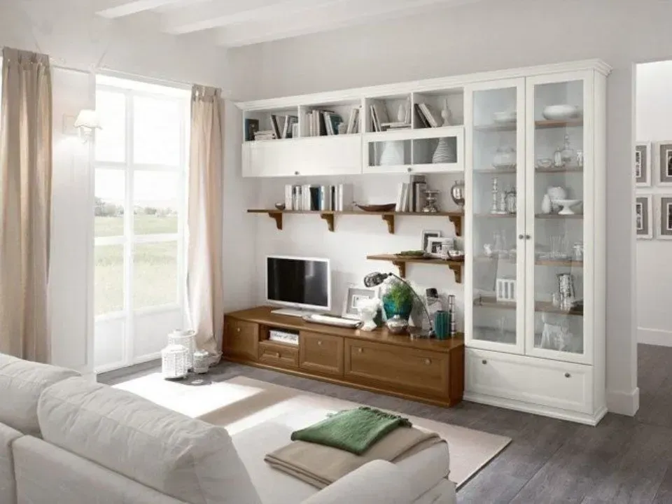 Soggiorno con divano bianco, mobile porta TV in legno e scaffali.