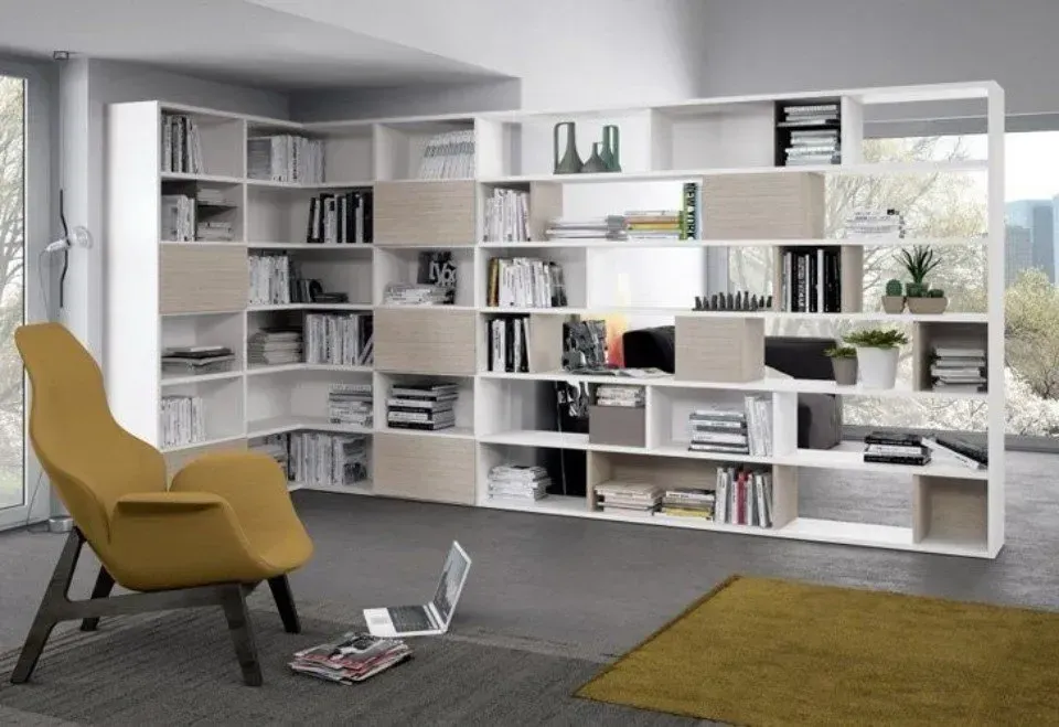 Moderna libreria bianca nell'angolo con sedia e computer portatile.