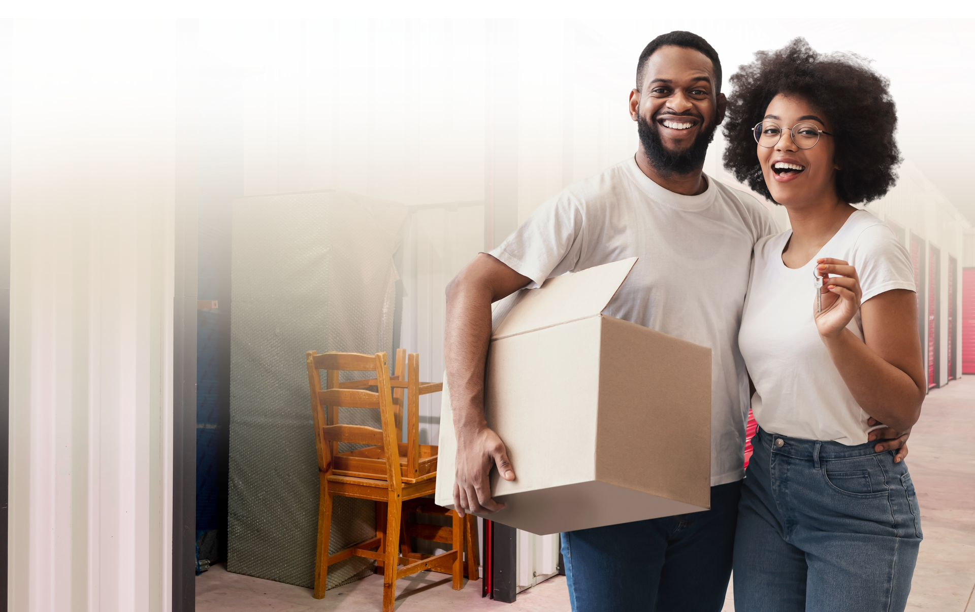 Woman holding two boxes in a storage unit, giving a thumbs up.