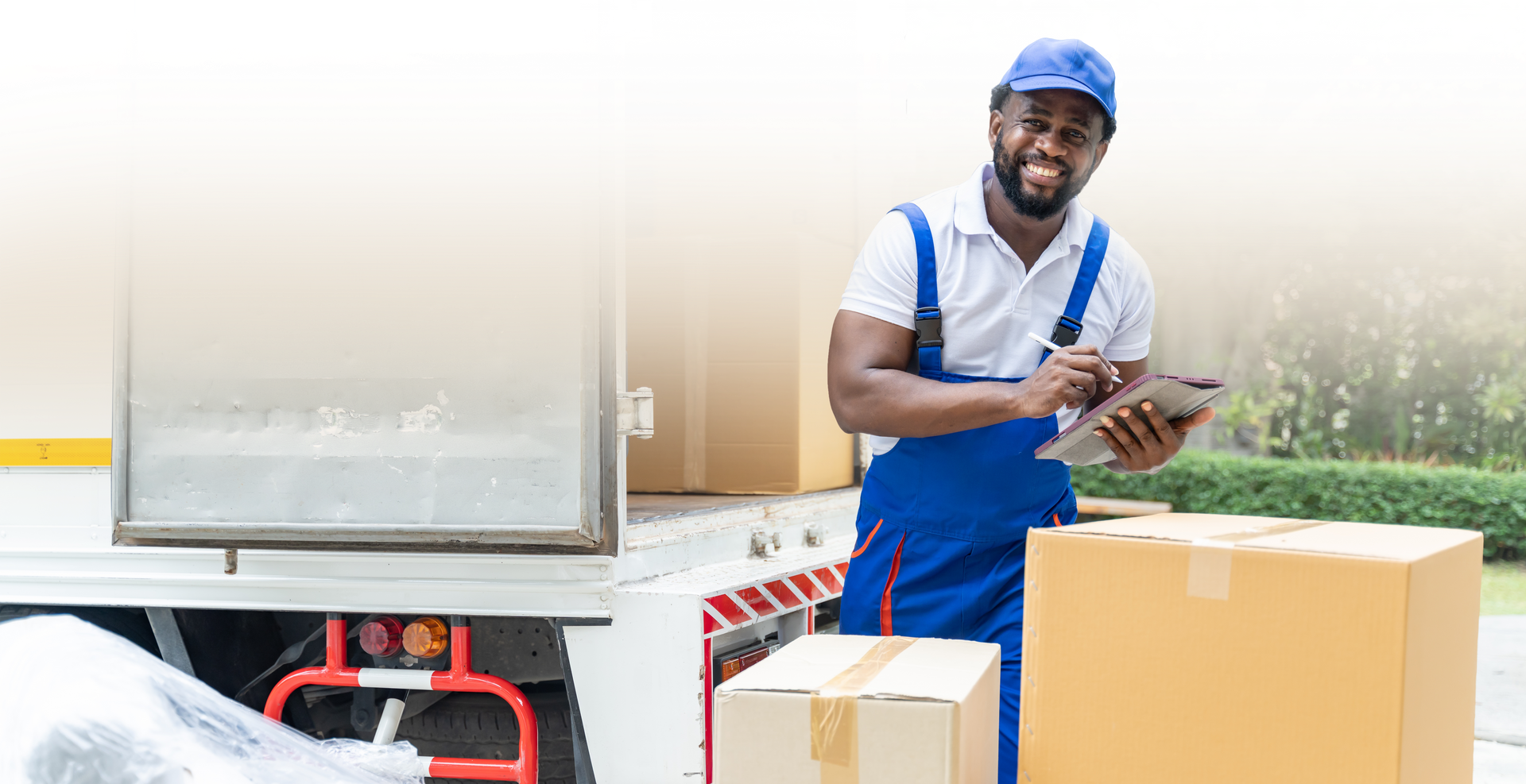 Two movers in red shirts and caps load boxes into a white moving truck.