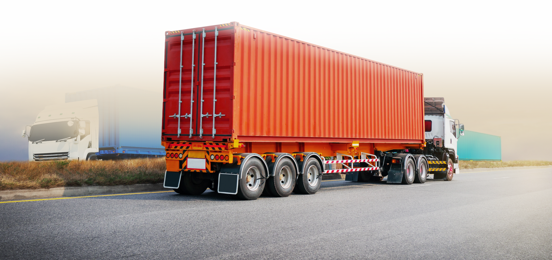 A semi-truck with an orange cargo container is on a road.