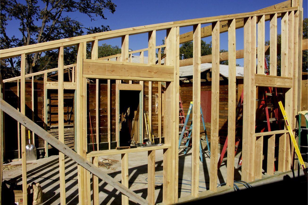Wooden frame of a building under construction, showing walls, windows, and door openings.