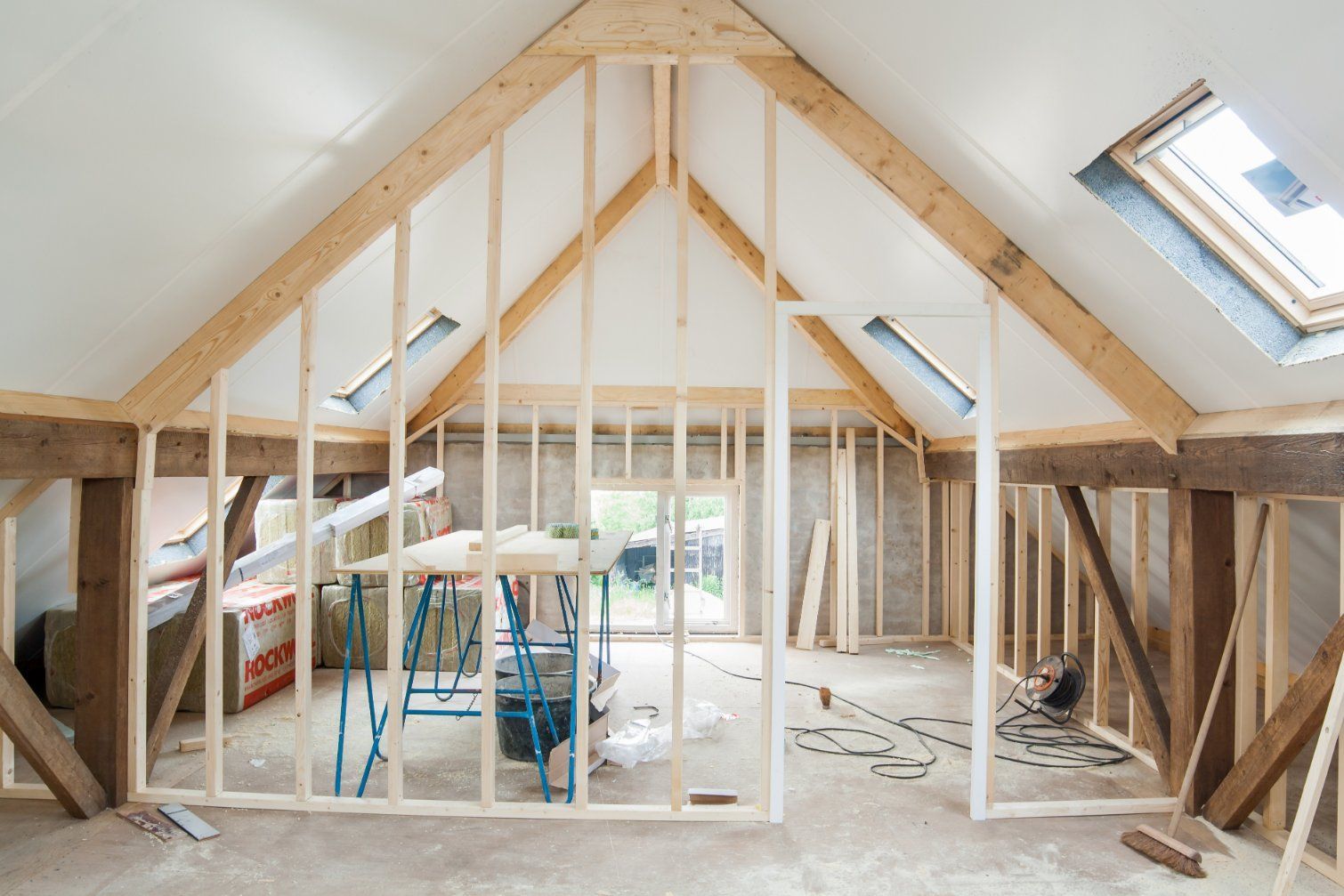 Interior view of an unfinished attic space with wooden framing, exposed beams, and skylights.