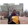 A woman is holding a piece of paper in front of a building.