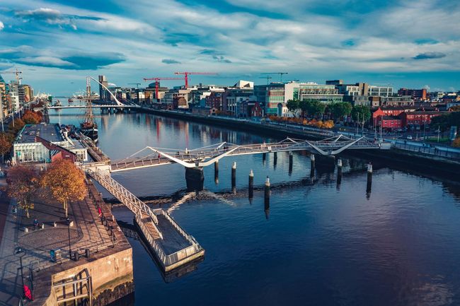 Aerial view of a river city with bridges, waterfront buildings, and a partly cloudy sky