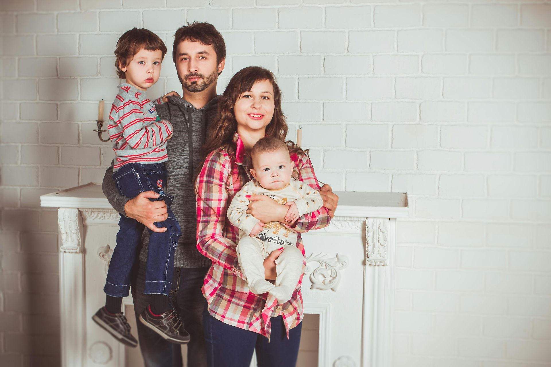 A family is posing for a picture in front of a fireplace.