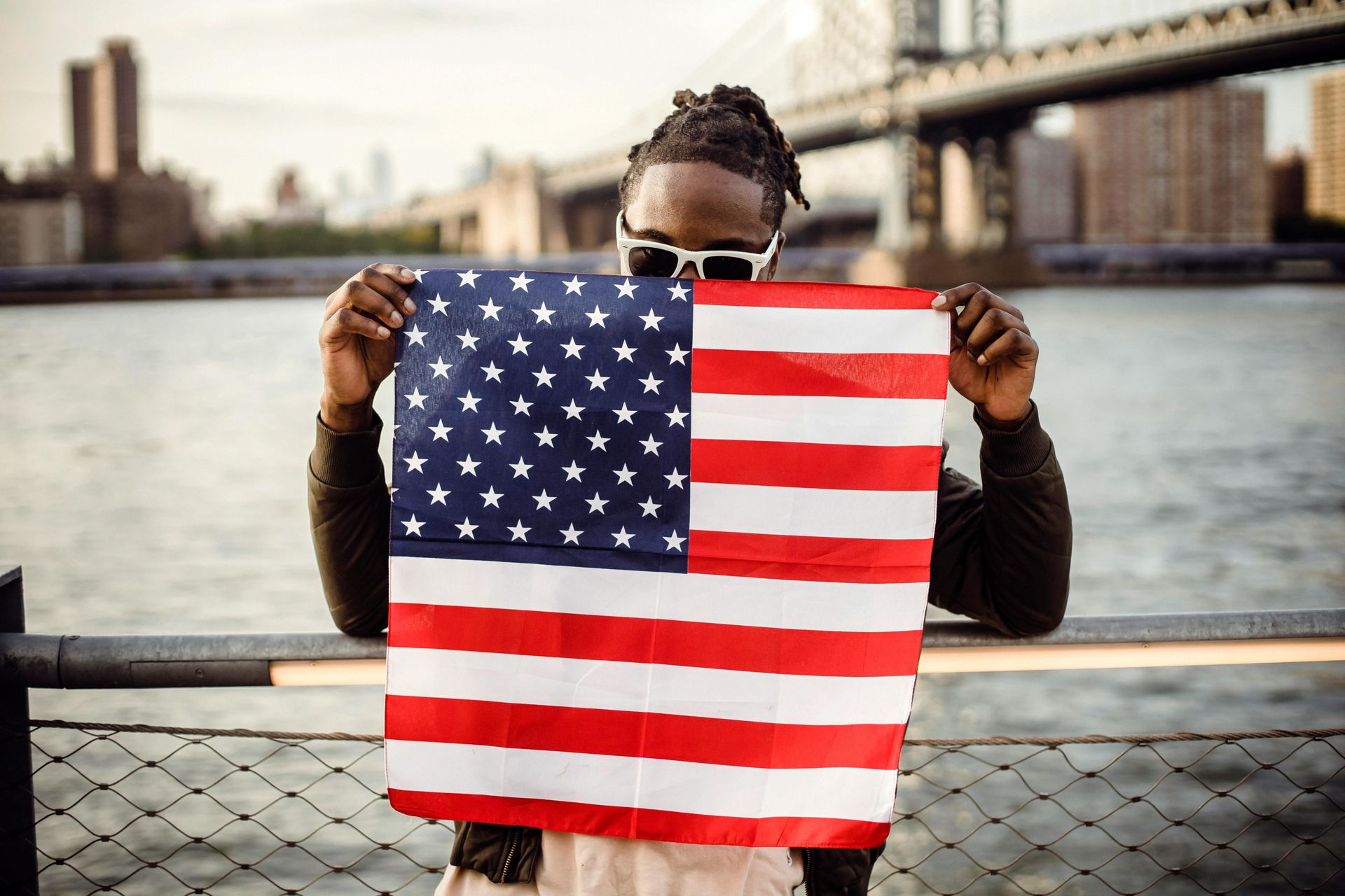 A man is holding an american flag in front of his face.