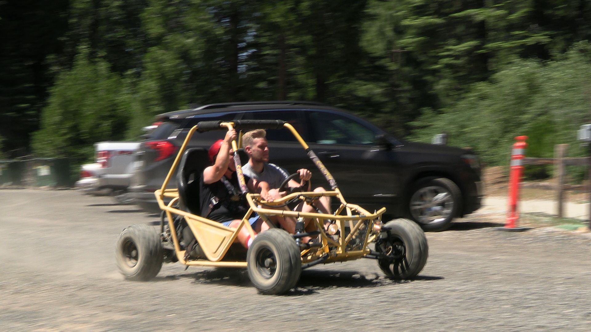 Two people are riding a buggy in a parking lot.