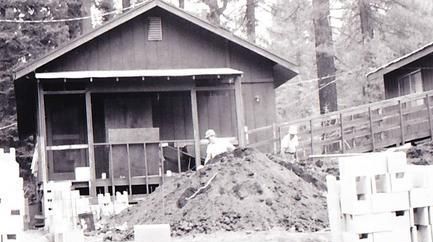 A black and white photo of a house with a pile of dirt in front of it.