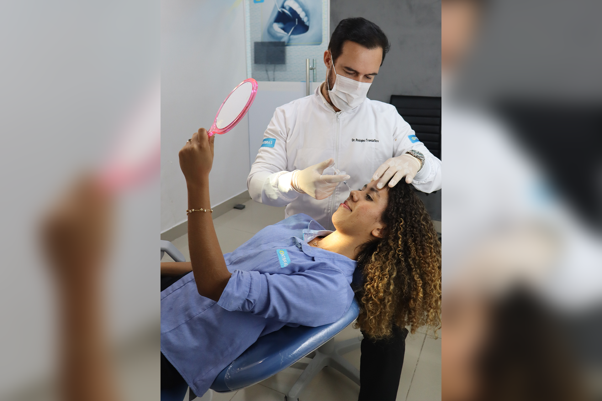 um homem de camisa azul está sorrindo na frente de uma placa.