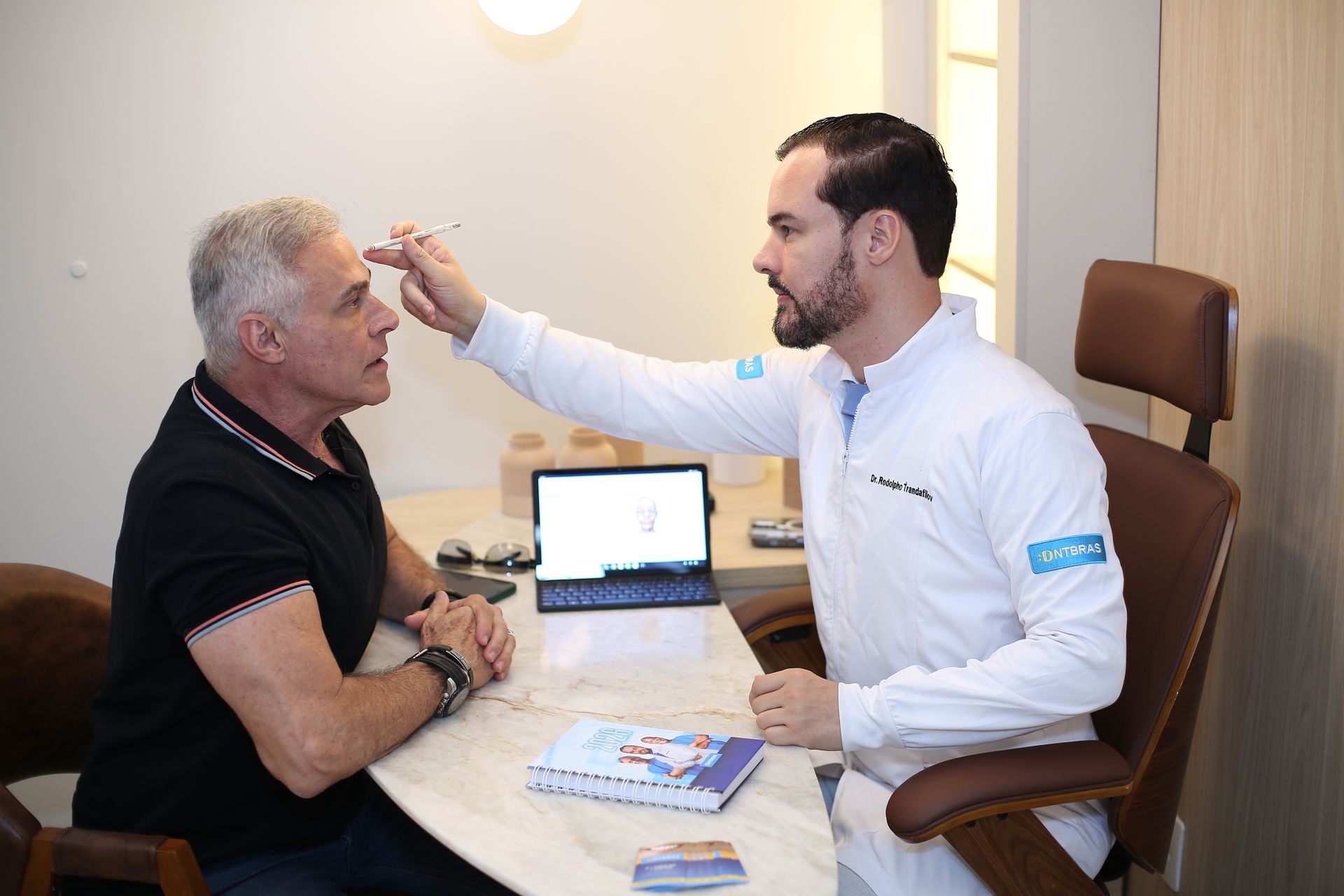 um homem de camisa azul está sorrindo na frente de uma placa.