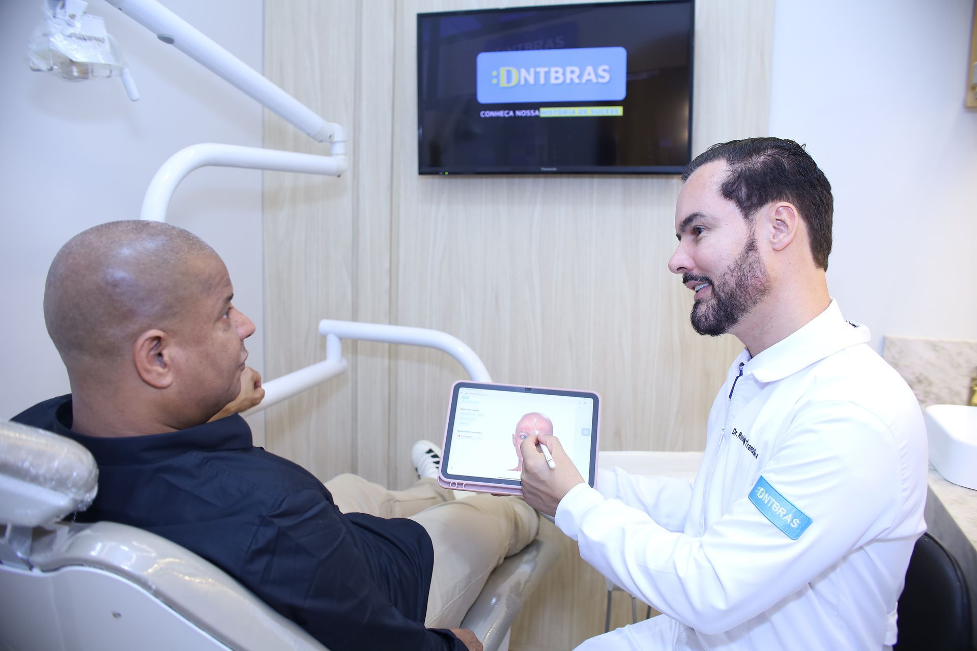 um homem de camisa azul está sorrindo com os braços cruzados.