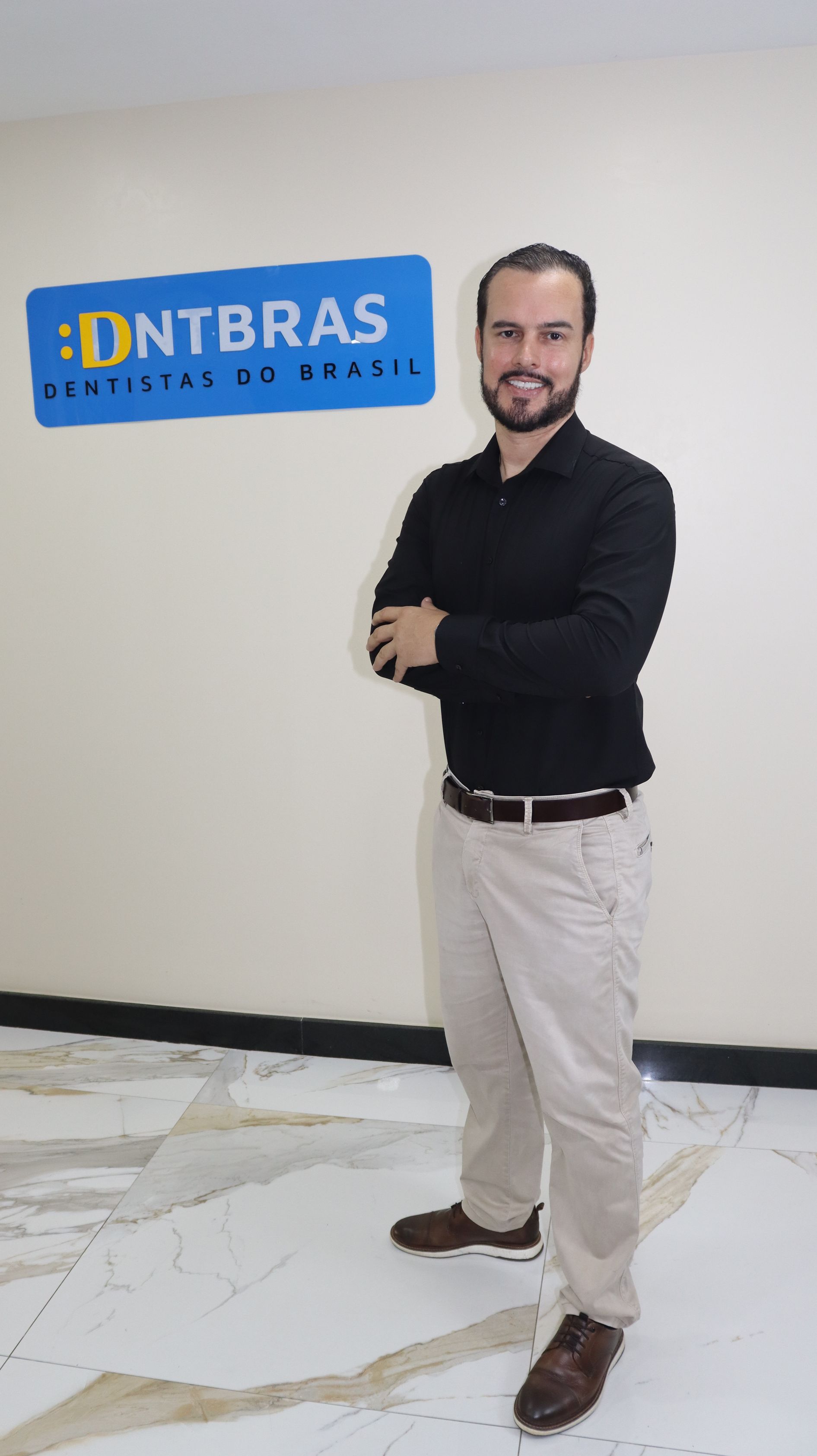 um homem de terno e gravata está parado em frente a uma cortina preta.