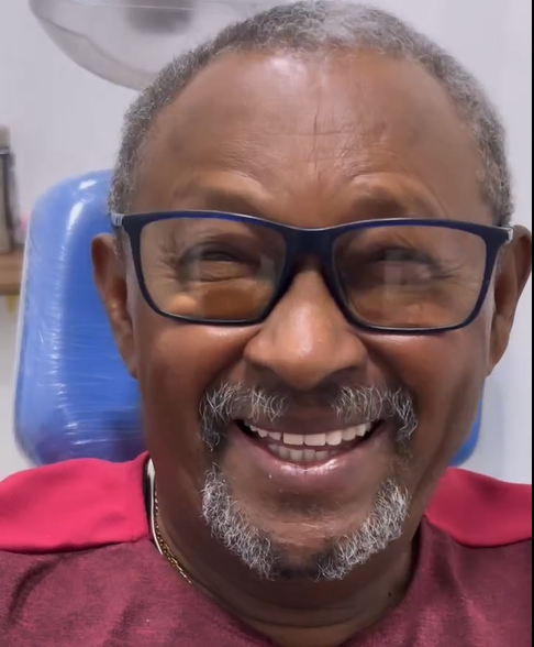 um homem de óculos e camisa vermelha está sorrindo