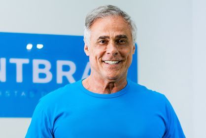 um homem de camisa azul está sorrindo na frente de uma placa.
