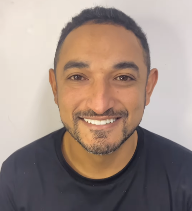 um homem com barba está sorrindo e vestindo uma camisa preta