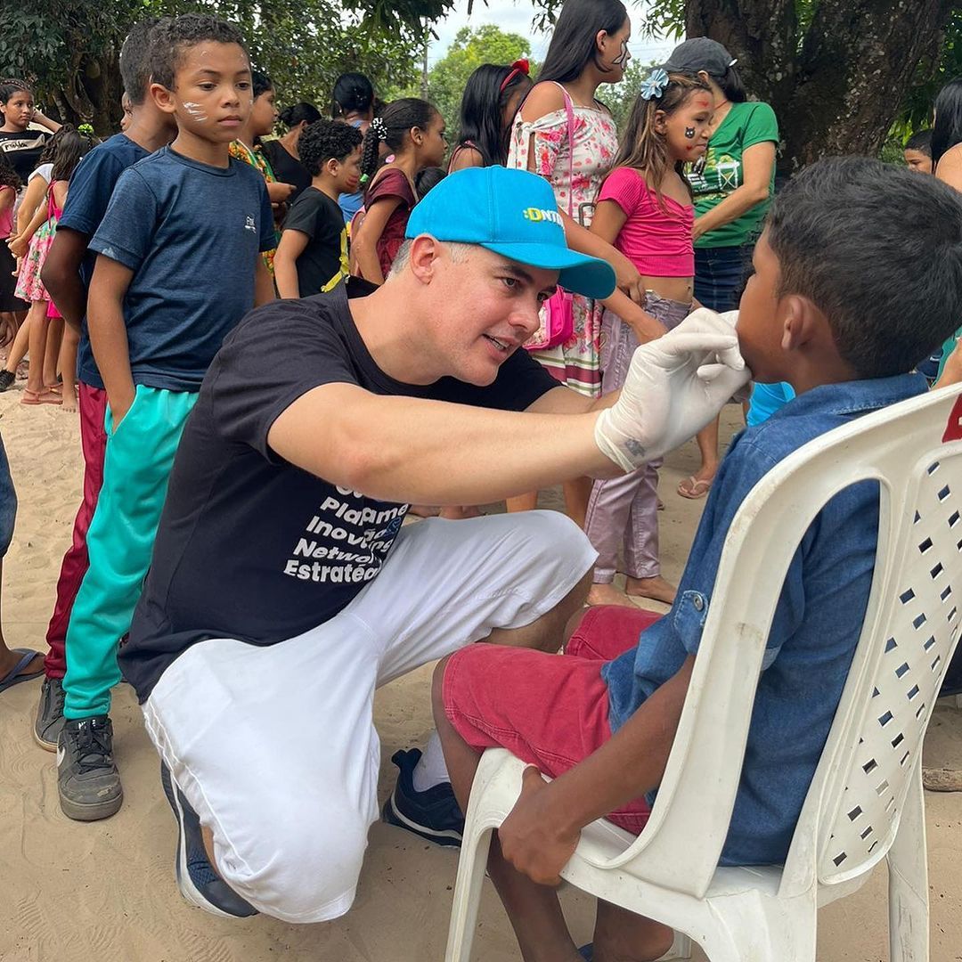 um homem de chapéu azul está ajoelhado ao lado de um menino em uma cadeira branca