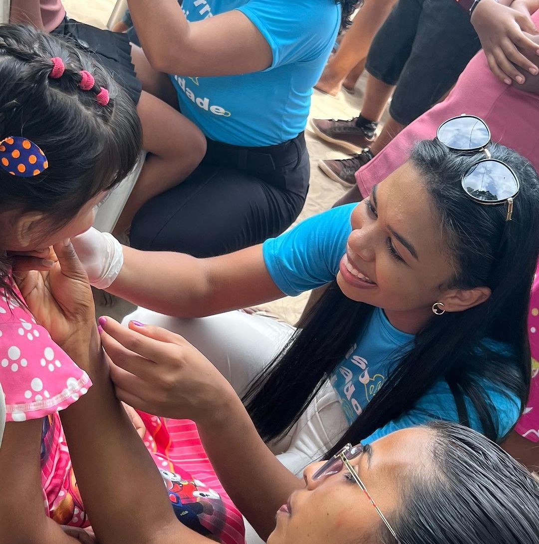uma mulher de camisa azul está segurando a mão de uma menina