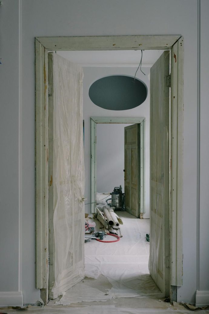 Doorway in a damaged interior corridor with peeling paint and debris on the floor.