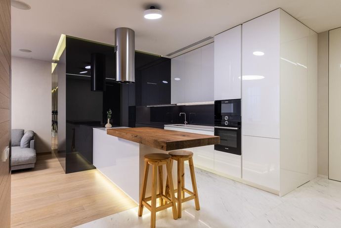 Modern kitchen with white cabinets, black backsplash, wooden island, and two stools