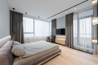 Modern minimalist bedroom with low bed, large windows, sheer curtains, and wall-mounted TV